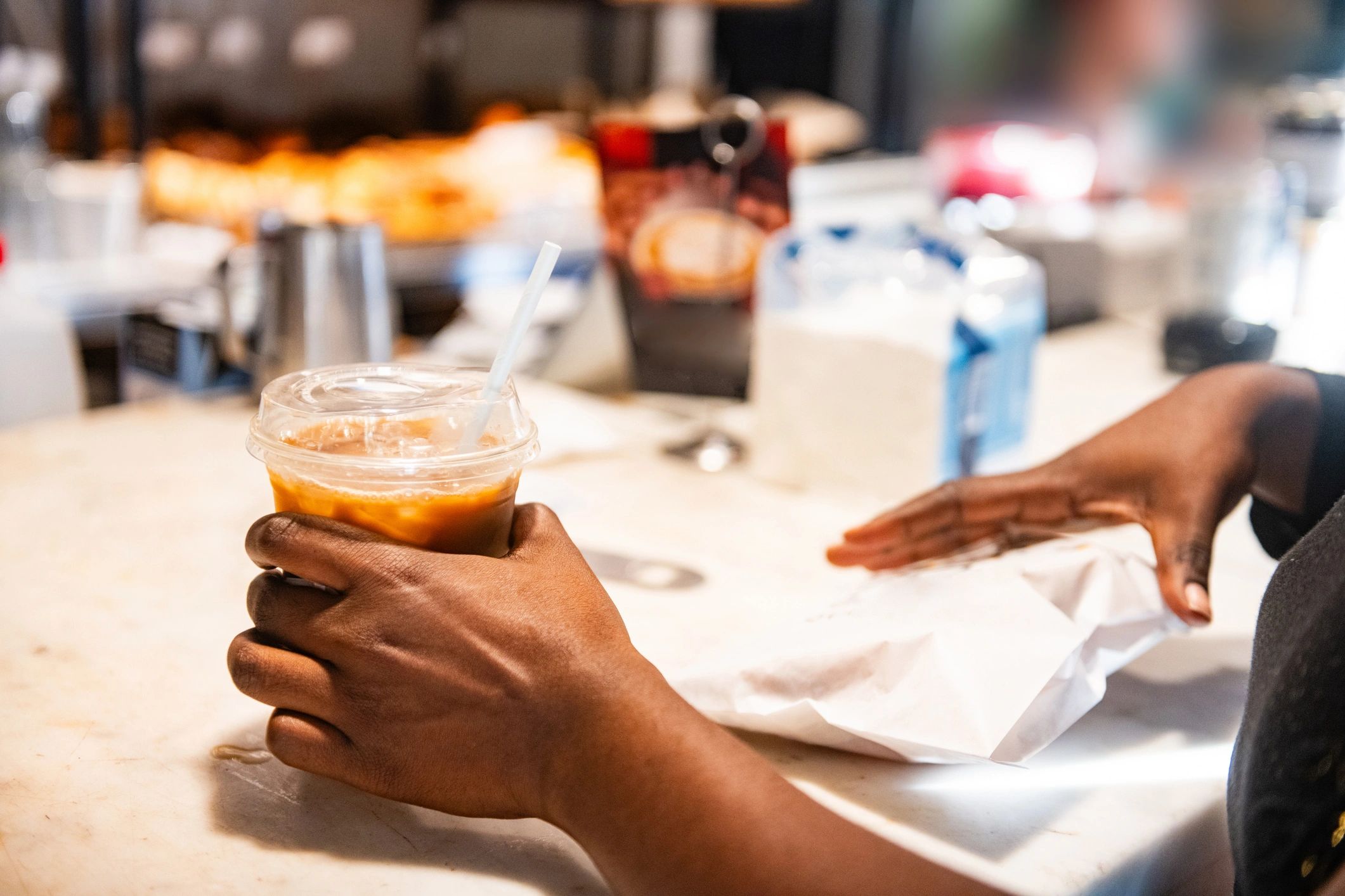 Hands picking up coffee at a counter